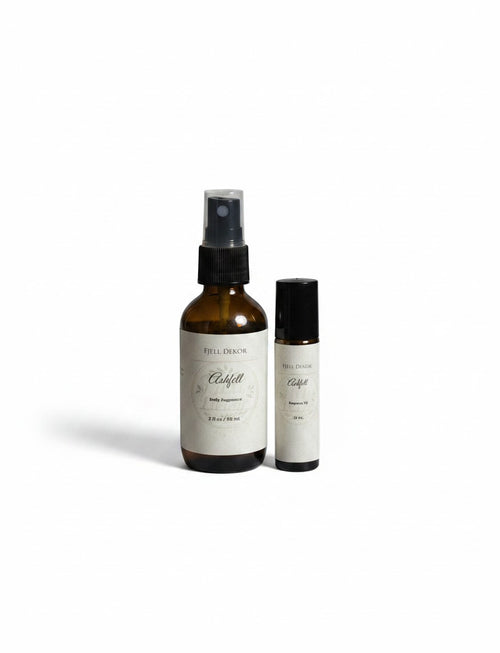 Fjell Dekor Ashfell body fragrance duo featuring a 2oz amber glass spray bottle and a 10ml rollerball perfume.