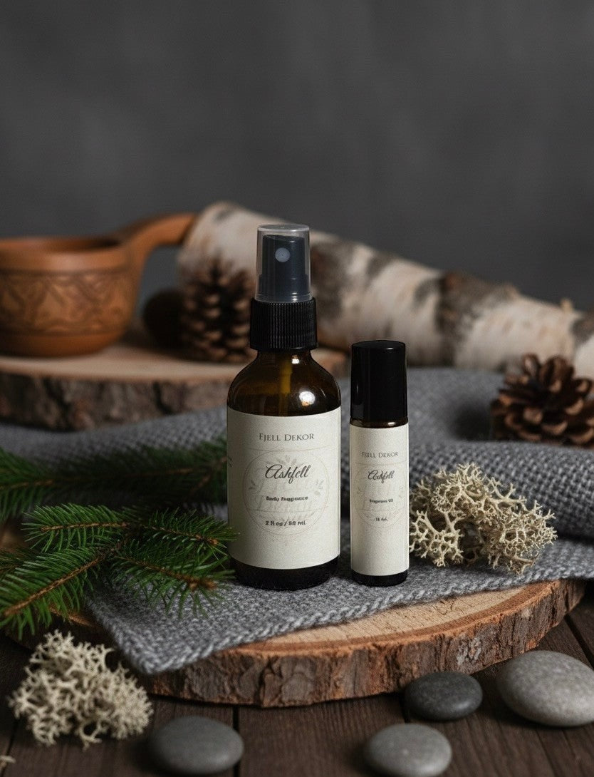 Fjell Dekor Ashfell fragrance duo with body mist and rollerball on a rustic wooden surface with pine and birch decor.