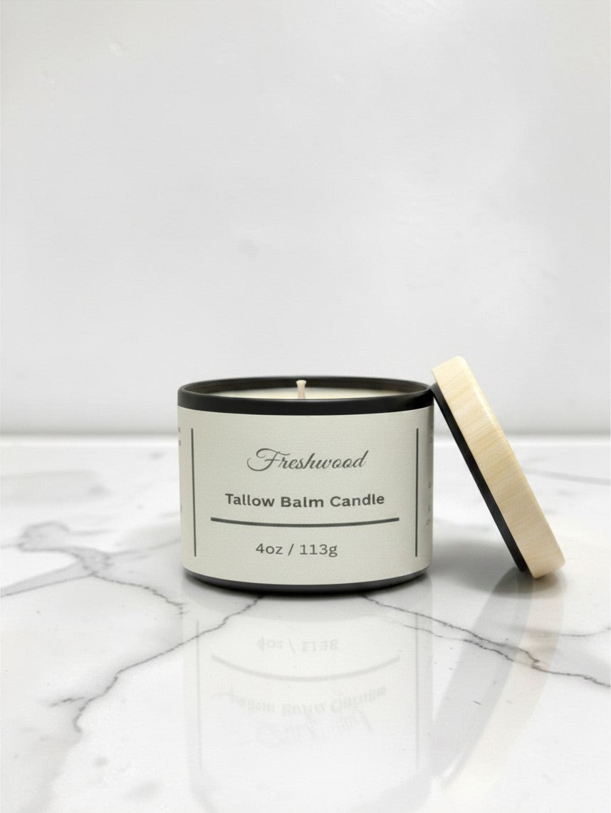 Fjell Dekor Freshwood tallow balm candle in a black jar with a light wood lid on a white marble surface.