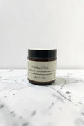Fjell Dekor Nesting Balm 4oz moisture-lock elasticity belly balm in an amber glass jar on a white marble surface.