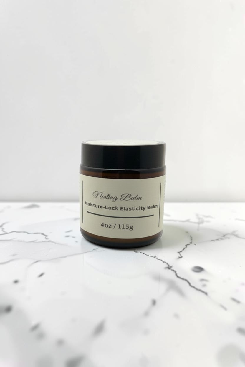 Fjell Dekor Nesting Balm 4oz moisture-lock elasticity belly balm in an amber glass jar on a white marble surface.