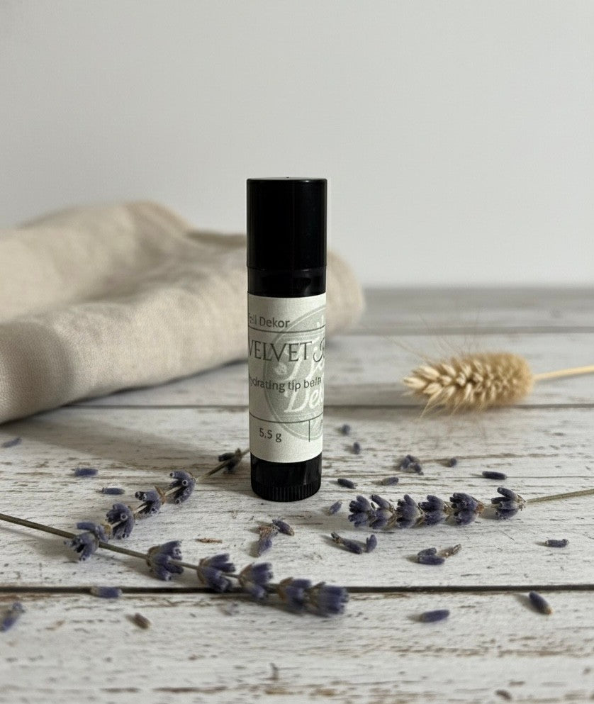 Fjell Dekor Velvet Kiss 5.5g natural lip balm tube on a rustic wooden surface with dried lavender and linen fabric.